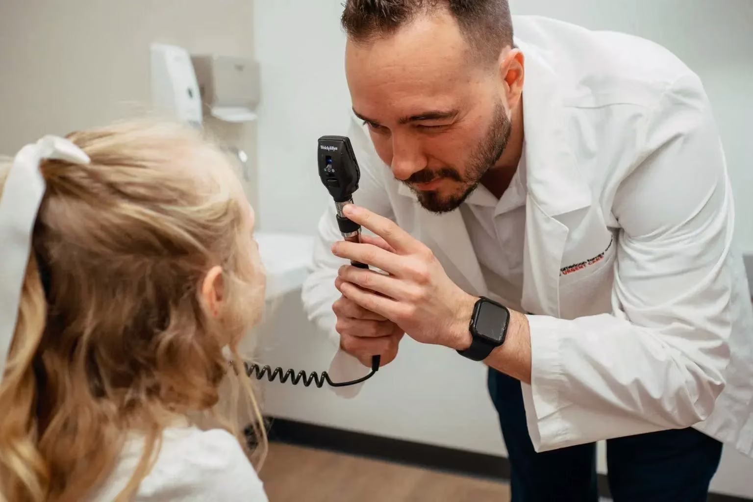 Male Medical Physician preforming an eye exam on on a young female child at AFC