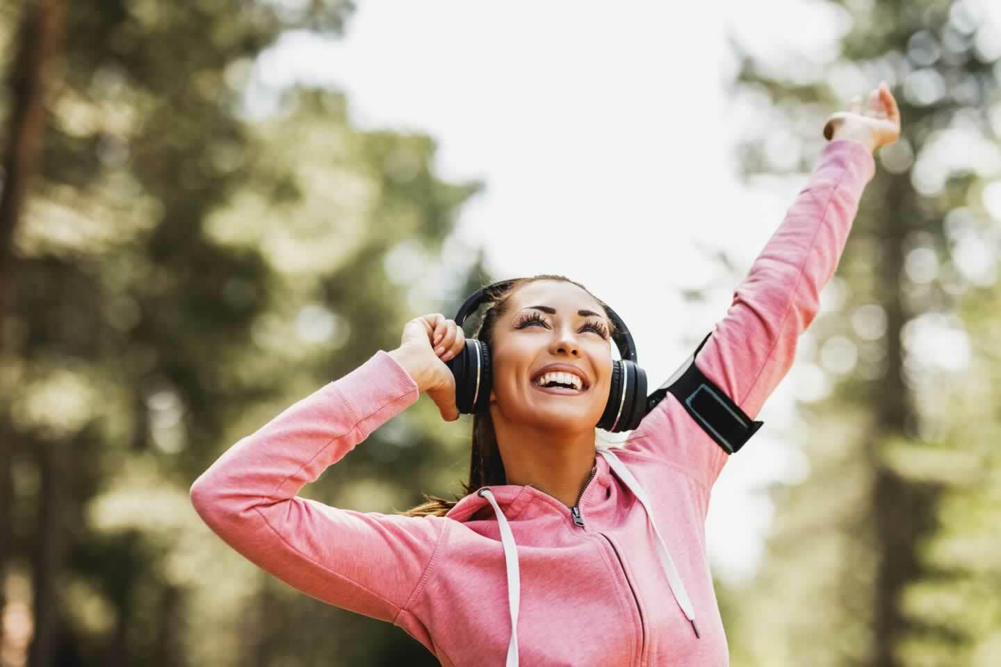 A smiling person jogging in a park under a sunny sky, representing the positive impact of exercise on mood.