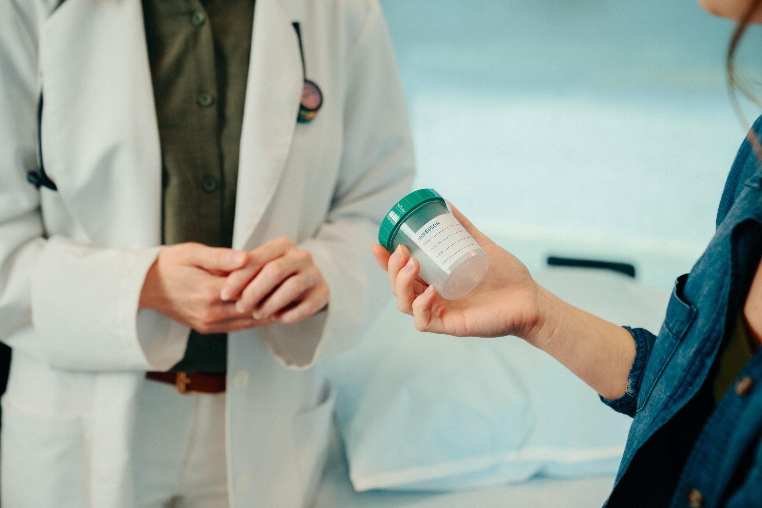 Woman holding a cup in preparation of her drug testing.
