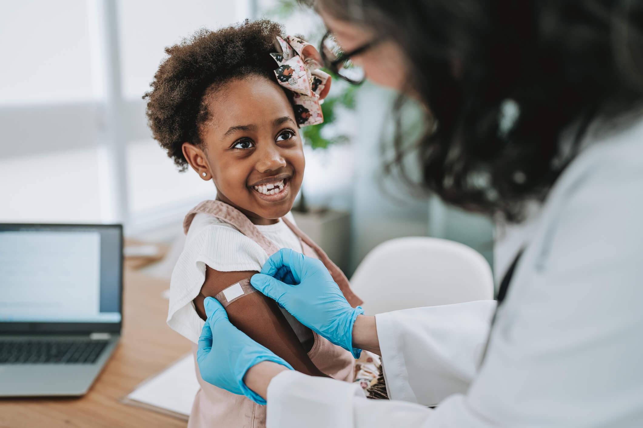 An image depicting a child receiving a vaccination from a healthcare professional in a clinical setting.