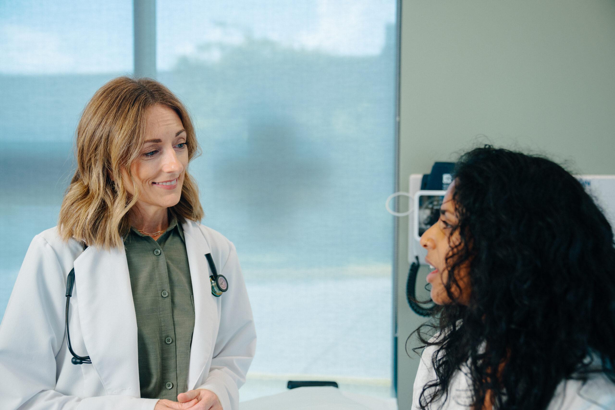 AFC healthcare provider discussing UTI or yeast infection symptoms with a patient in an AFC examination room.