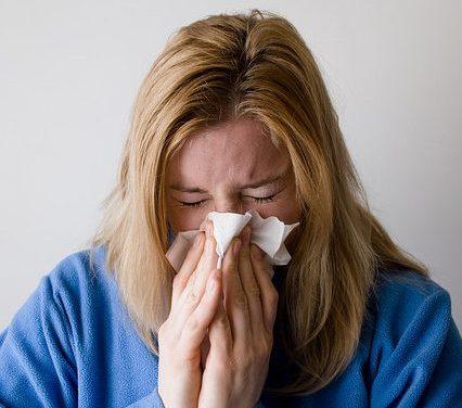 sick woman with flu blowing nose