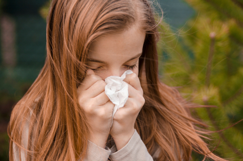 girl sneezes from seasonal illness and flu