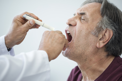 man gets sore throat checked by doctor