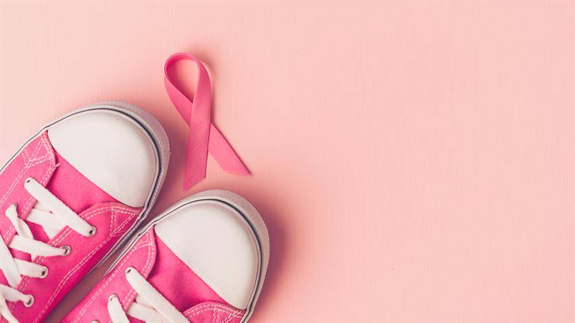 Pink sneakers and a pink ribbon on a pale pink background, symbolizing breast cancer awareness, emphasize the link between regular check-ups at your local medical center and early detection.