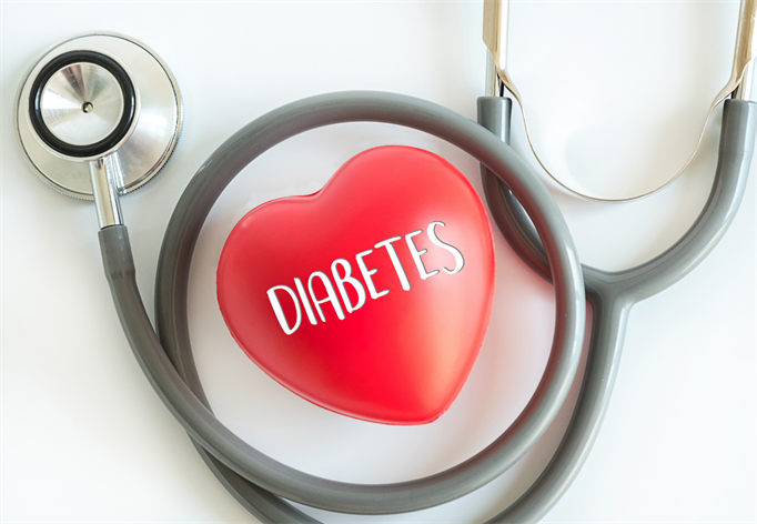 A stethoscope surrounds a red heart-shaped object with the word "DIABETES" written on it, symbolizing the connection between diabetes and heart health, often addressed in urgent care settings.