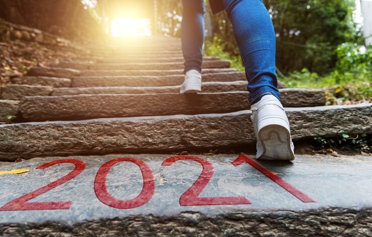Person wearing jeans and white sneakers climbing stone steps with "2021" printed on one of the steps, possibly heading to an urgent care facility nearby. Sunlight shines through trees at the top of the steps.