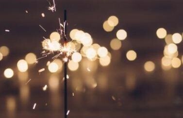 A lit sparkler with bright sparks is in focus, set against a blurred background of circular bokeh lights, reminiscent of the bustling yet serene atmosphere found in an urgent care medical center.