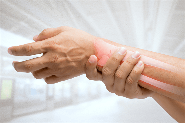 A hand holding a wrist with an illustration of a highlighted bone, suggesting joint or bone pain in the wrist area, emphasizes the need for a medical consultation. Consider visiting a walk-in clinic or medical center for prompt assessment and treatment.