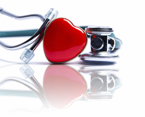 A red heart-shaped object and a stethoscope lie on a reflective white surface, subtle symbols of care and dedication often seen at a walk-in clinic.