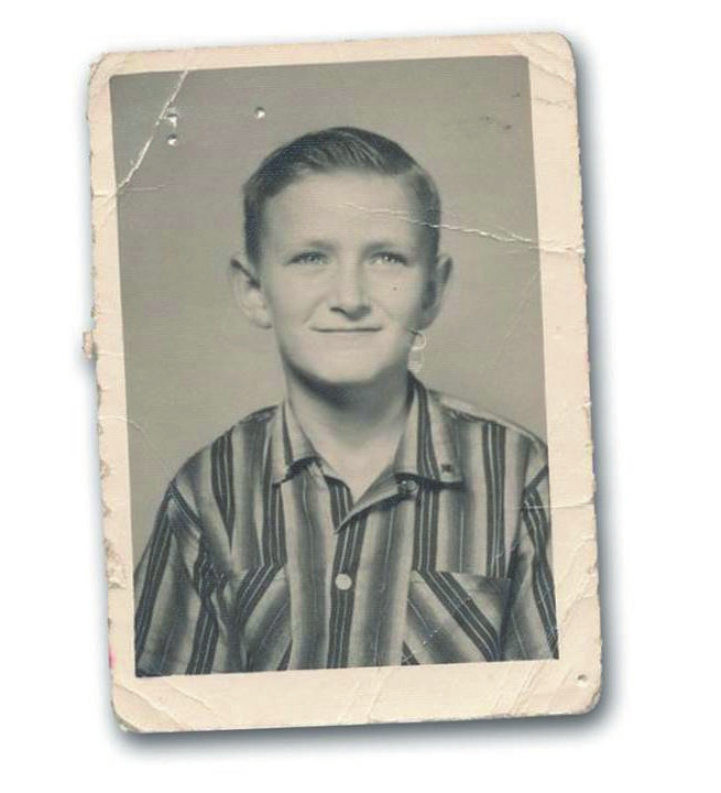 A black-and-white photograph of a young boy wearing a striped shirt, displayed in an aged, creased frame, reminiscent of the waiting area at an old walk-in clinic.