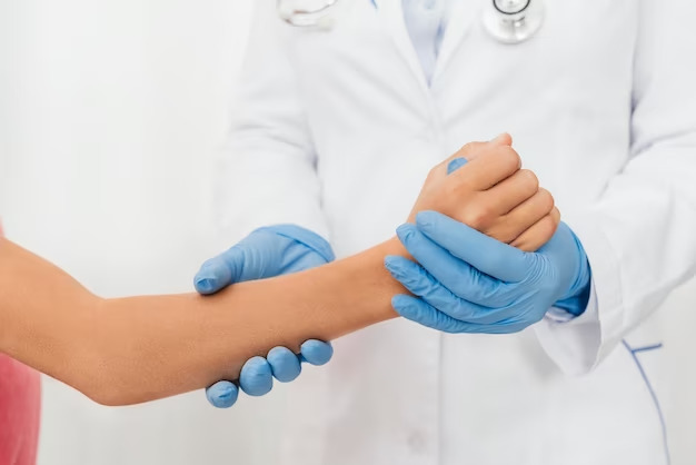 At the walk-in clinic, a person in a white coat and stethoscope checks another person's wrist while wearing blue gloves.