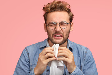 Man about to sneeze into a tissue because he came down with the flu