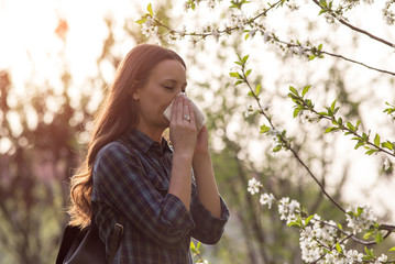 Woman blowing her nose as the colder season begins and is worried she might contract RSV, the flu or another upper respiratory infection