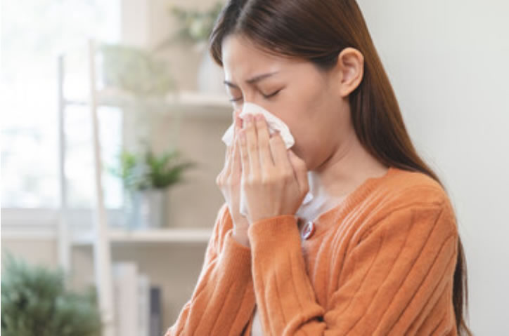 Woman blowing her nose and is unsure if it’s Flu, RSV or something else