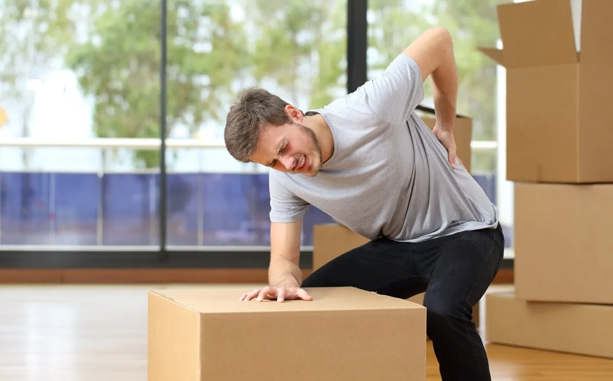 Man suffering back injury from moving boxes