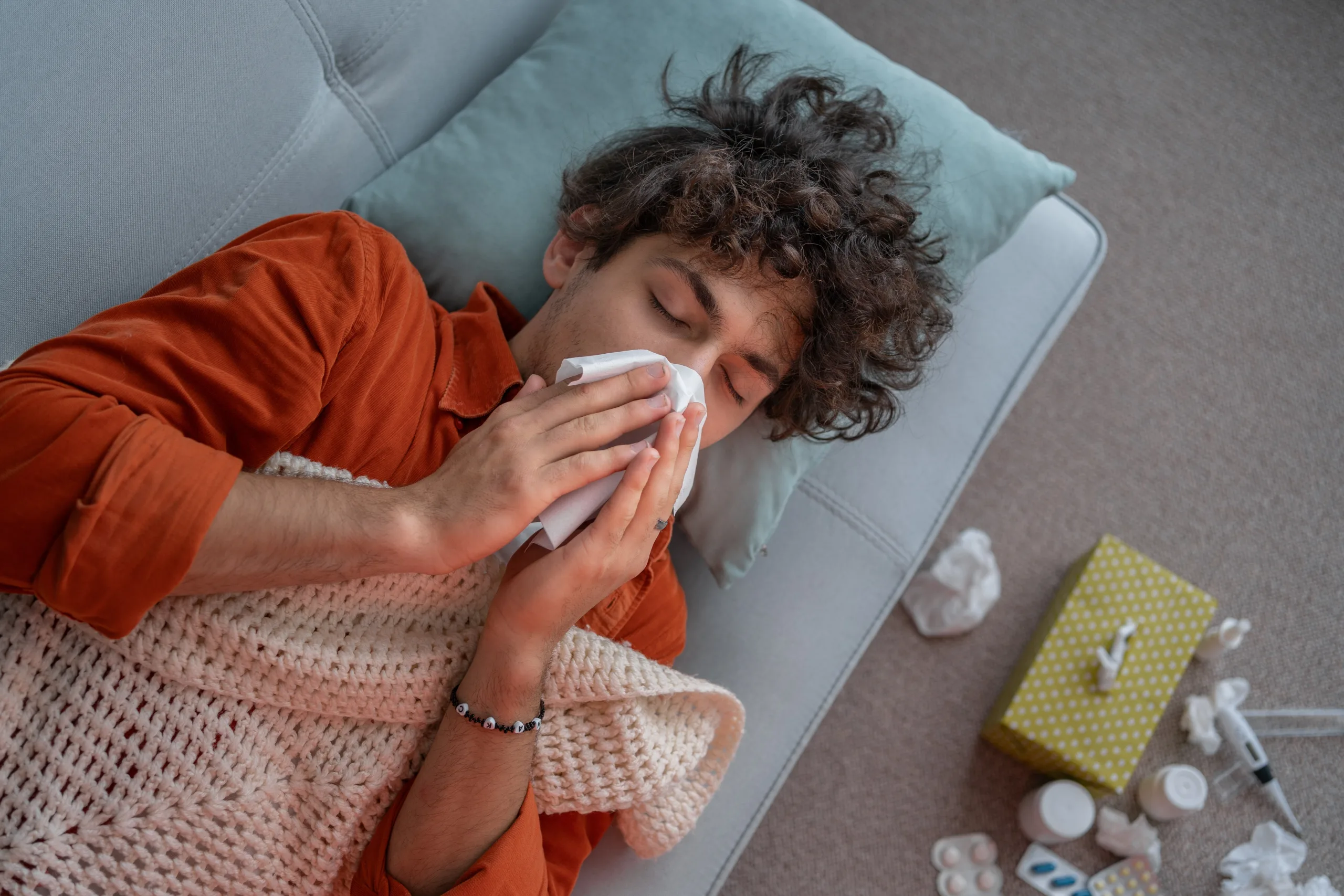 Young Man on Couch Blowing His Nose