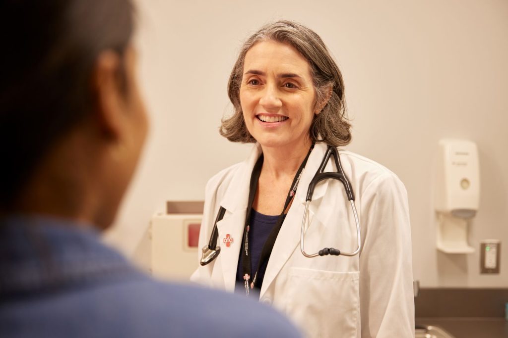 A doctor with a stethoscope conversing with a patient in a clinical setting